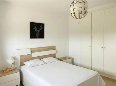 a bedroom with a white bed and a chandelier at Apartamento moderno con vistas in El Puerto de Santa María