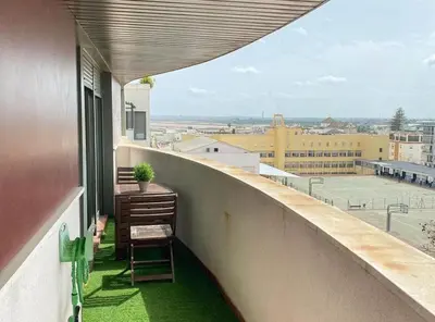 a chair on a balcony with a view of a city at Apartamento moderno con vistas in El Puerto de Santa María