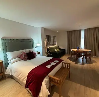 a bedroom with a large bed and a dining room at Apartamentos Turísticos La Plaza in Chipiona