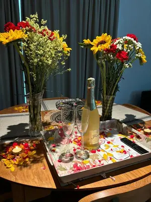 a table with flowers and a bottle of wine and glasses at Apartamentos Turísticos La Plaza in Chipiona