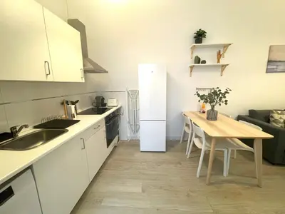a kitchen with a table and a white refrigerator at El Patio de Santa María in Cádiz