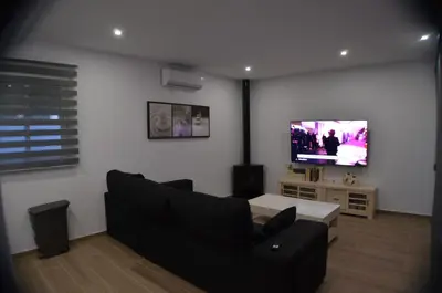 a living room with a black couch and a tv at EL ENCANTO Chiclana II in Chiclana de la Frontera