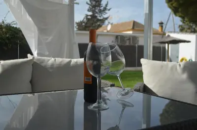 a bottle of wine and two wine glasses on a table at EL ENCANTO Chiclana II in Chiclana de la Frontera