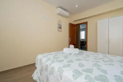 a bedroom with a bed with a green and white comforter at Casa Caleta in Cádiz
