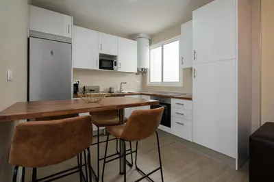 a kitchen with white cabinets and a wooden table and stools at Casa Caleta in Cádiz