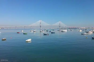 a bridge over a large body of water with boats at Casa Caleta in Cádiz