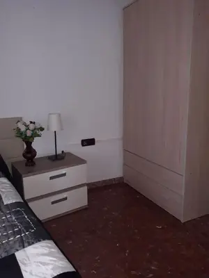 a bedroom with a bed and a dresser with a lamp at Cadiz Rented in Cádiz