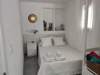 a white bedroom with a bed with two towels on it at Casa Mundaka in Sanlúcar de Barrameda