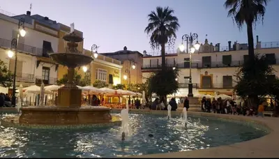 a fountain in the middle of a square with buildings at Casa Mundaka in Sanlúcar de Barrameda