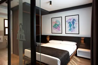 a bedroom with a bed and two paintings on the wall at Apartamentos La Espadaña in Rota