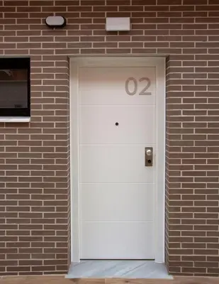 a white door on a brick building with the number at Apartamentos La Espadaña in Rota