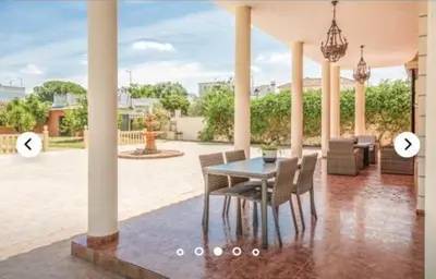 a dining table and chairs on a patio with two pictures of a house at HIDALMAR in Arcos de la Frontera