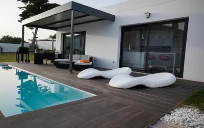 a house with a swimming pool with two white chairs next to it at VILLA ANYWAY CONIL Un lujo frente al mar in Conil de la Frontera