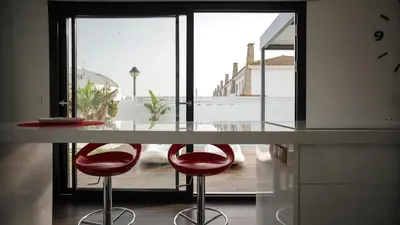 a kitchen with two red stools at a counter at VILLA ANYWAY CONIL Un lujo frente al mar in Conil de la Frontera