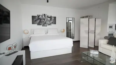 a white bedroom with a white bed and a couch at VILLA ANYWAY CONIL Un lujo frente al mar in Conil de la Frontera