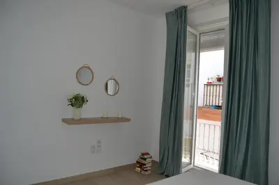 a bedroom with a green curtain and a window at APARTAMENTO LUPA in Cádiz