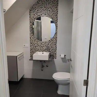 a bathroom with a toilet and a sink and a mirror at Ohana in San Fernando