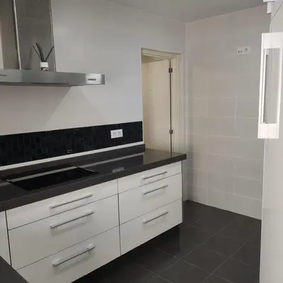 a kitchen with white cabinets and a black counter top at Ohana in San Fernando