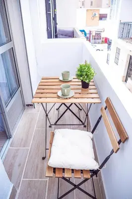 a small balcony with a wooden table and chairs at Apartamento AGUADULCE in Sanlúcar de Barrameda