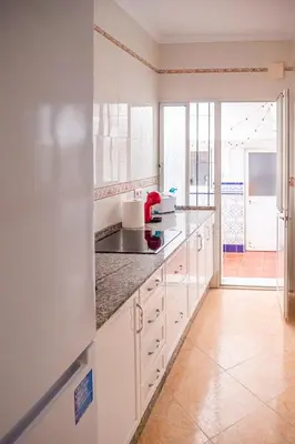 a kitchen with white cabinets and a large window at Apartamento AGUADULCE in Sanlúcar de Barrameda