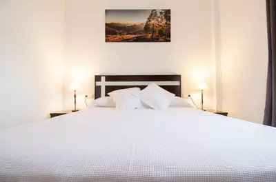a bedroom with a large white bed with two lamps at Casa Sumariva in Sanlúcar de Barrameda