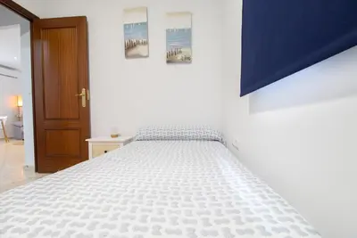 a white bed in a bedroom with a blue wall at Casa Sumariva in Sanlúcar de Barrameda