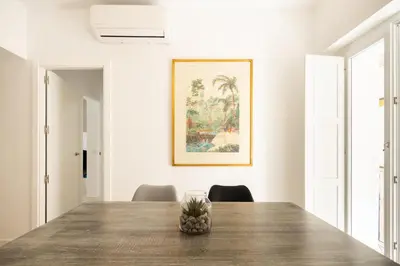a dining room with a wooden table and a picture on the wall at Suite Catedral Little Apartments in Cádiz