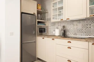 a kitchen with white cabinets and a stainless steel refrigerator at Suite Catedral Little Apartments in Cádiz