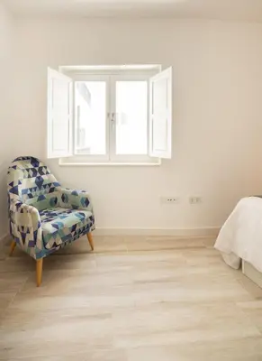 a bedroom with a chair and a window at Suite Catedral Little Apartments in Cádiz