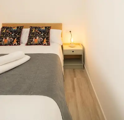 a bedroom with a bed and a side table with a lamp at Suite Catedral Little Apartments in Cádiz