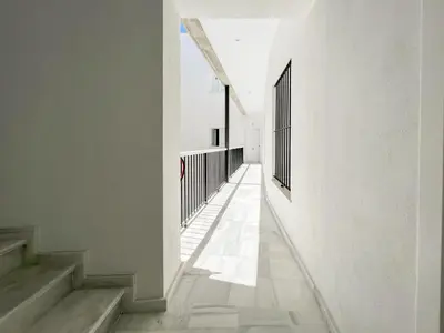 a corridor of a building with white walls and stairs at Suite Catedral Little Apartments in Cádiz