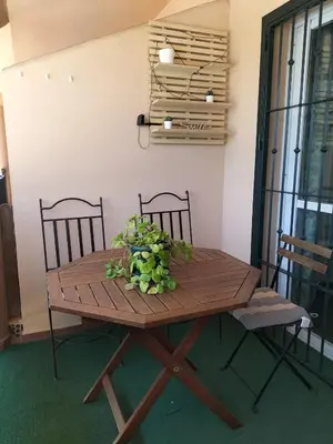a wooden table with chairs and a vase of flowers on it at APARTAMENTO EN URBANIZACIÓN AL-ÁNDALUs CERCA DE LA PLAYA DE LA BARROSA in Chiclana de la Frontera