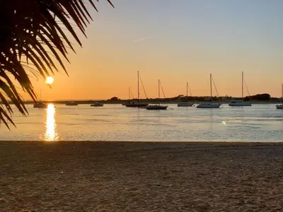 a group of boats in the water at sunset at APARTAMENTO EN URBANIZACIÓN AL-ÁNDALUs CERCA DE LA PLAYA DE LA BARROSA in Chiclana de la Frontera