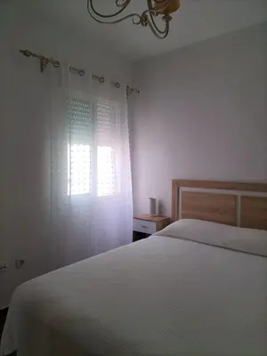 a bedroom with a white bed and a window at APARTAMENTO EN URBANIZACIÓN AL-ÁNDALUs CERCA DE LA PLAYA DE LA BARROSA in Chiclana de la Frontera