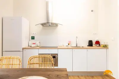 a kitchen with white cabinets and a wooden table at Carpenter's Home by Cadiz Time in Cádiz