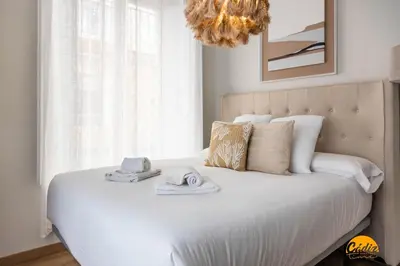 a bedroom with a white bed with towels and a chandelier at Carpenter's Home by Cadiz Time in Cádiz