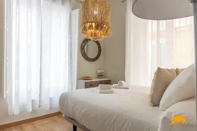 a bedroom with a large white bed and a chandelier at Carpenter's Home by Cadiz Time in Cádiz