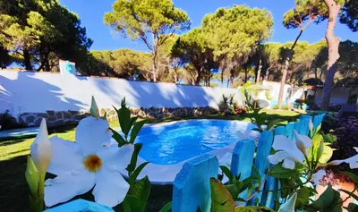 a swimming pool in a garden with white flowers at Villa Zahara in Chiclana de la Frontera