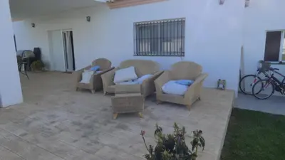 a patio with three chairs and a couch at Villa Olivia con Piscina, Jardin y Parking in Chiclana de la Frontera