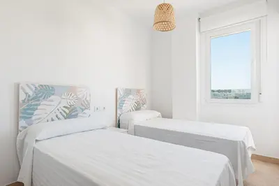 two beds in a white room with a window at Casa Playa Andres in Conil de la Frontera