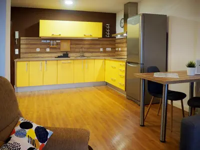 a kitchen with yellow cabinets and a table and a refrigerator at Loft con encanto cerca del centro + Parking in Jerez de la Frontera