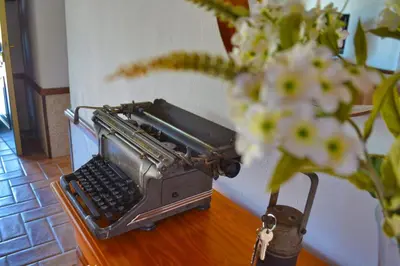 an old typewriter on a table next to a vase with flowers at La Esperanza in Medina Sidonia