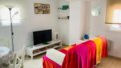 a room with a bed with colorful sheets and a tv at Ático Cádiz Playa in Cádiz