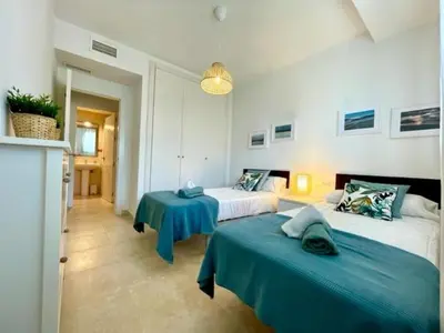 a bedroom with two beds and a blue table at GATU PREMIUM Racimo, terraza, aire ac, piscina comun, wifi y parking 