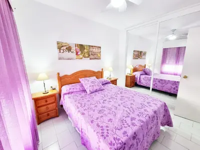 a bedroom with a purple bed and a mirror at Dunas y Luz in Rota