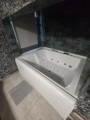 a white bath tub in a bathroom with a tile wall at Latorre jacuzzi jerez in Jerez de la Frontera