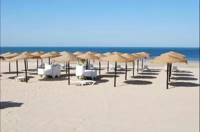 a beach with chairs and umbrellas and the ocean at Chipiona Apartamento Bajo Centro Parking Incluido WiFi GRATIS in Chipiona