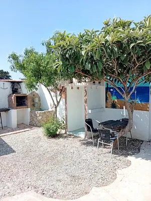 a table and chairs under a tree on the beach at Casa del abuelo antonioTrujillo in Conil de la Frontera