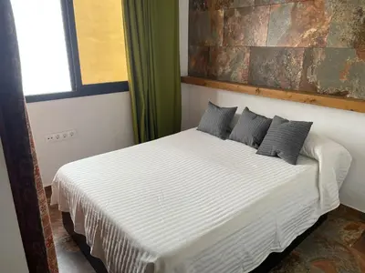 a bedroom with a white bed with black pillows at Casa Amelie in Hozanejos