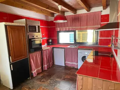 a red kitchen with a sink and a washing machine at Casa Amelie in Hozanejos
